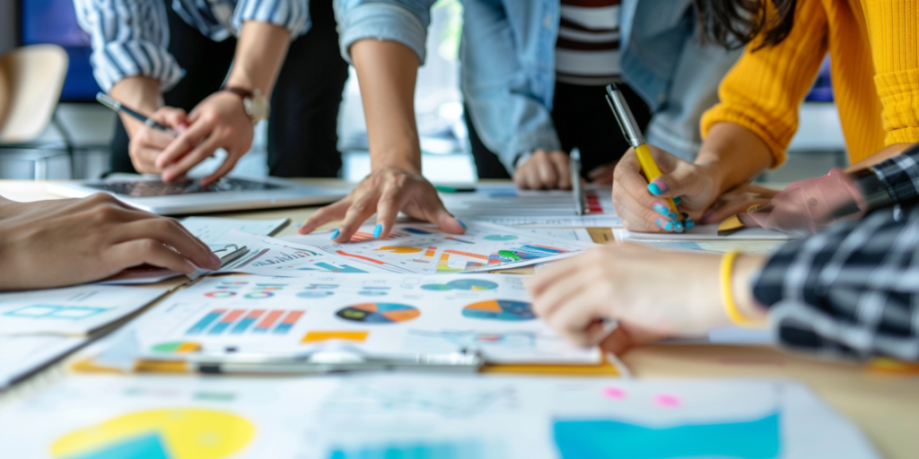 ludzie planujący strategię marketingową na dużym stole z kartkami z wykresami i diagramami